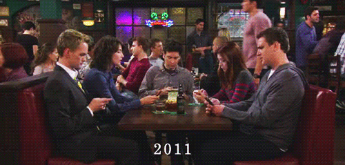 gif showing the cast of How I Met Your Mother at a table in the pub, everyone is on their phone