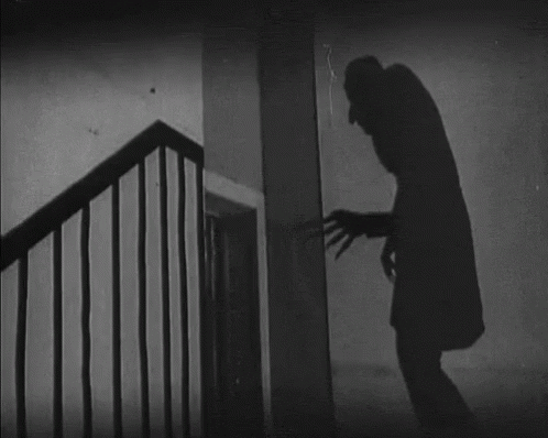 gif of the long, tall shadow of Nosferatu from the original black and white movie, reaching a clawed hand toward a door 