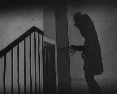 gif of the long, tall shadow of Nosferatu from the original black and white movie, reaching a clawed hand toward a door
