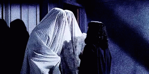 gif from the movie Beetlejuice where Lydia is trying to peek beneath the bedsheets worn by two ghosts