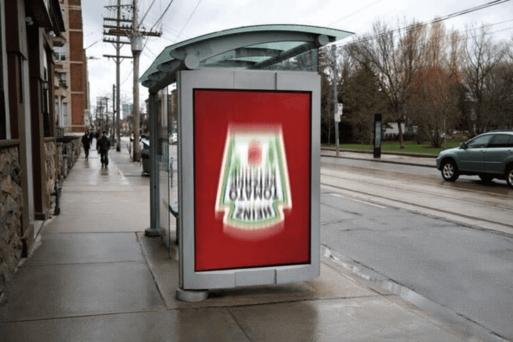 photo of a Heinz bus bench ad that's entirely red with their logo upside down and blurred as if being shaken like a bottle of ketchup 